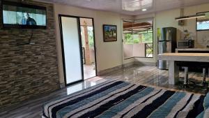 een woonkamer met een tv aan een bakstenen muur bij House in the Woods in Guápiles