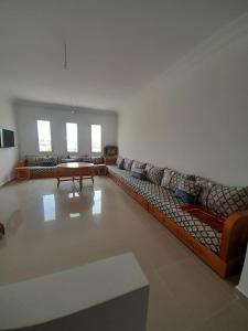 a living room with a long couch and a table at Entre Vagues et Saveurs Votre Oasis à Fnideq in Fnidek
