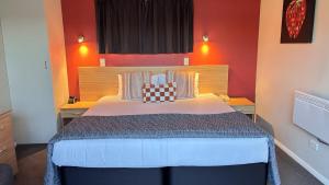 a bedroom with a large bed with red walls at Arcadia Motel in Nelson