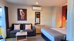 a hotel room with a bed and a couch at Arcadia Motel in Nelson