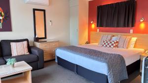 a bedroom with a bed and a couch in a room at Arcadia Motel in Nelson