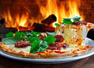 una pizza sentada en un plato delante de un fuego en Acacia Snowy Motel en Jindabyne