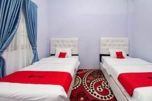 two beds sitting next to each other in a room at RedDoorz Syariah at Masrun Homestay Bangkinang in Bangkinang
