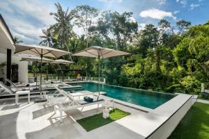 an outdoor pool with chairs and umbrellas at Villa Aikyam in Tegalalang