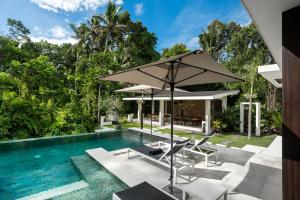 an outdoor pool with a table and chairs and an umbrella at Villa Aikyam in Tegalalang