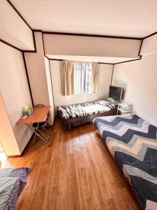 a room with two beds and a desk and a window at Shinjuku Wasabi House II in Tokyo