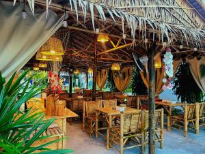 a restaurant with tables and chairs under a straw umbrella at Leelawadee Bungalow and Restaurant in Mae Nam