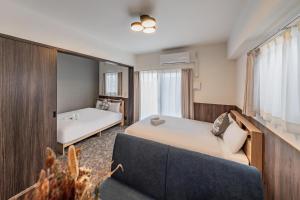 a room with two beds and a couch and a tub at Apartment Hotel 11 Abeno in Osaka
