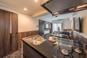 a kitchen with a sink and a living room at Apartment Hotel 11 Abeno in Osaka