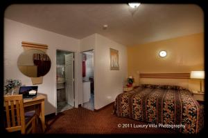 a hotel room with a bed and a desk and a bathroom at The Palace Inn in Oxnard