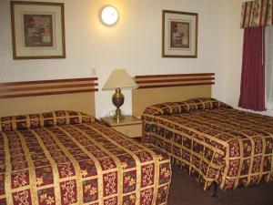 a hotel room with two beds and a lamp at The Palace Inn in Oxnard
