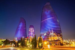 three tall skyscrapers lit up in blue at night at Elit Continental Hotel in Baku