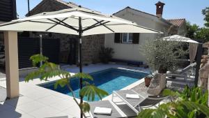 ombrellone e sedie accanto alla piscina di Villa Nostalgia pool & wellness a Gračišče