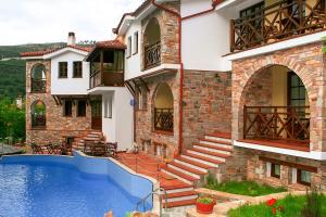 a house with a swimming pool in front of it at Kazaviti Luxury Suites in Mikrós Prínos