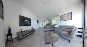 a living room with two couches and a flat screen tv at חלון לים - דירת נופש באכזיב in Nahariyya