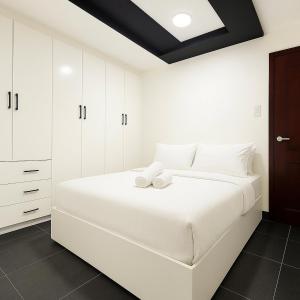a bedroom with a large white bed with white cabinets at Modern and Stylish Bachelors Pad in San Josef