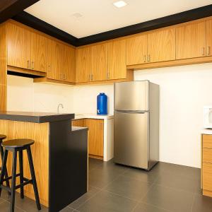 a kitchen with a stainless steel refrigerator and wooden cabinets at Modern and Stylish Bachelors Pad in San Josef