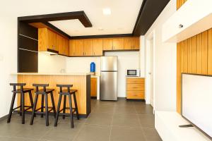a kitchen with wooden cabinets and bar stools at Modern and Stylish Bachelors Pad in San Josef