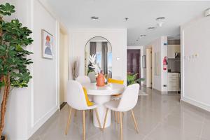 une salle à manger avec une table et des chaises blanches dans l'établissement Silkhaus Modern 2 BDR | Sea View | Oceanscape, à Abu Dhabi