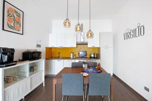 una cocina con armarios blancos y una mesa de madera con sillas. en Residence Virgilio Yellow, en Toscolano Maderno
