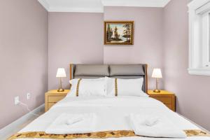 una camera da letto con un grande letto bianco con due lampade di Modern Private 3BR House a Vancouver
