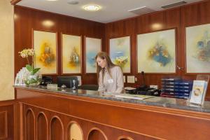 a woman standing at a counter in a waiting room at Hotel Villa Bacchus in Baška Voda