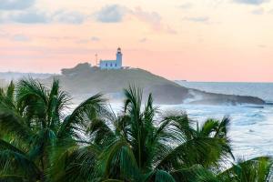 a lighthouse on an island in the ocean with palm trees at Coastal Express Inn & Suites #1 at 681 Ocean Drive in Arecibo