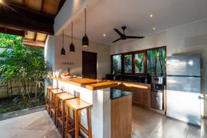 a kitchen with a bar with stools and a refrigerator at Villa Alroda Antik - Peaceful 4BR Villa with Private Pool in Canggu in Dalung
