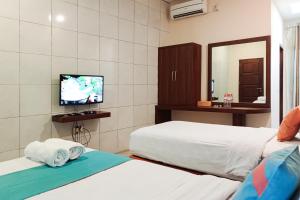 Una habitación de hotel con dos camas y un televisor. en Sans Hotel Grand Jitra Syariah Bengkulu, en Bengkulu