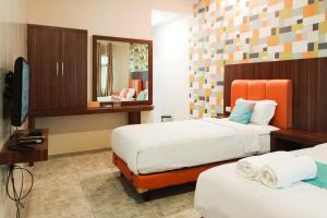 Una habitación de hotel con dos camas y un televisor. en Sans Hotel Grand Jitra Syariah Bengkulu, en Bengkulu