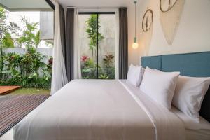 a bedroom with a large white bed and a large window at Sunny Village Berawa in Canggu