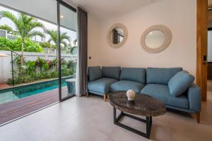 a living room with a blue couch and a table at Sunny Village Berawa in Canggu