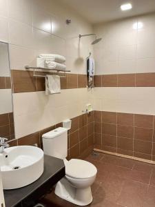 a bathroom with a white toilet and a sink at Hotel Adya Express Chenang in Pantai Cenang +51 photos