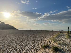 a sandy beach with the sun in the sky at Appart T2 Bidart Plage Huabia in Bidart