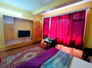 a bedroom with a bed and a tv and red curtains at Hotel Nirvana in Vashisht