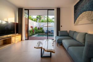 a living room with a blue couch and a television at Sunny Village Berawa in Canggu