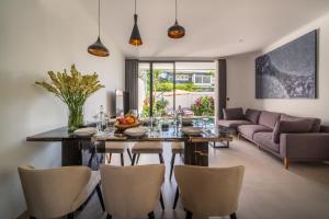 a dining room and living room with a table and chairs at Sunny Village Berawa in Canggu