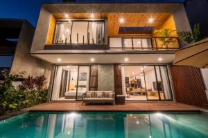 a house with a swimming pool in front of it at Sunny Village Berawa in Canggu