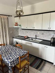 a kitchen with white cabinets and a table and a sink at Villa Nefeli in Ayios Nikolaos Sithonia +6 photos