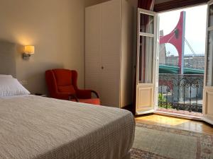 a bedroom with a bed and a chair and a window at Guggenhome Bilbao in Bilbao