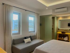 a bedroom with a bed and a couch and windows at Mykonos Dot Suites in Ano Mera +42 photos
