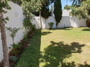 a backyard with a white fence and a grass yard at Chelly Bungalow en bord de mer in Nabeul +13 photos