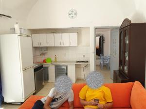 two people sitting on a couch in a kitchen at Chelly Bungalow en bord de mer in Nabeul