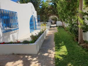 a garden with white walls and blue gates at Chelly Bungalow en bord de mer in Nabeul