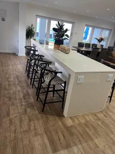 a kitchen with a large white counter with chairs at Riebeeck Villa - 5 min walk to Franschhoek Central in Franschhoek