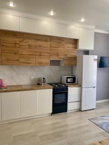 a kitchen with white appliances and wooden cabinets at Sat City block A in Astana