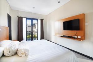 a bedroom with a bed with a tv on the wall at Mahabrahma Villa in Uluwatu +8 photos
