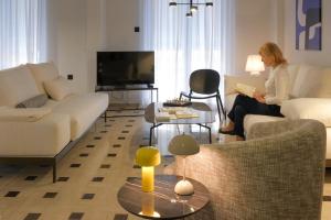 a woman sitting in a living room reading a book at AD ASTRA Comfort Living in Preveza