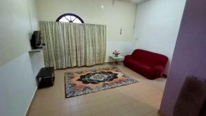 a living room with a red couch and a rug at HOMESTAY SEGAMAT - Impian Home 