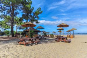 a group of picnic tables on a beach with umbrellas at Mobilhome Premium in Biscarrosse